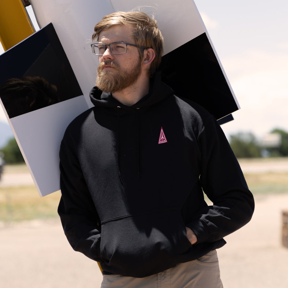 Man wearing a National Association of Rocketry Hoodie standing in front of a large rocket.
